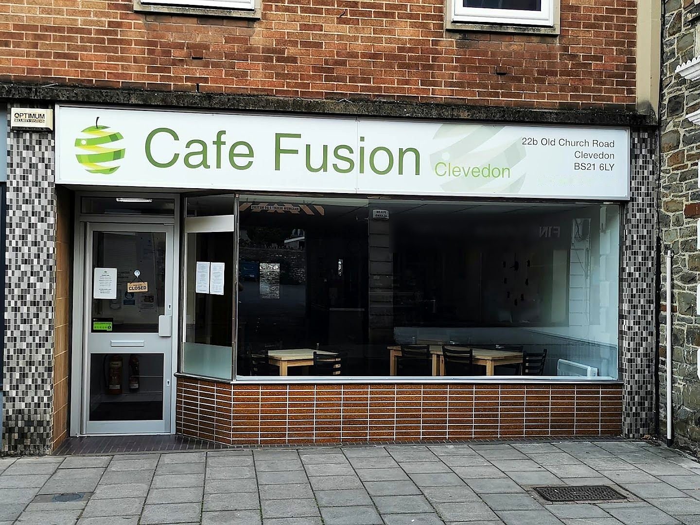 Cafe Fusion on Old Church Road, Clevedon: a white sign with a green apple logo above a glass shopfront, between brick and stone walls